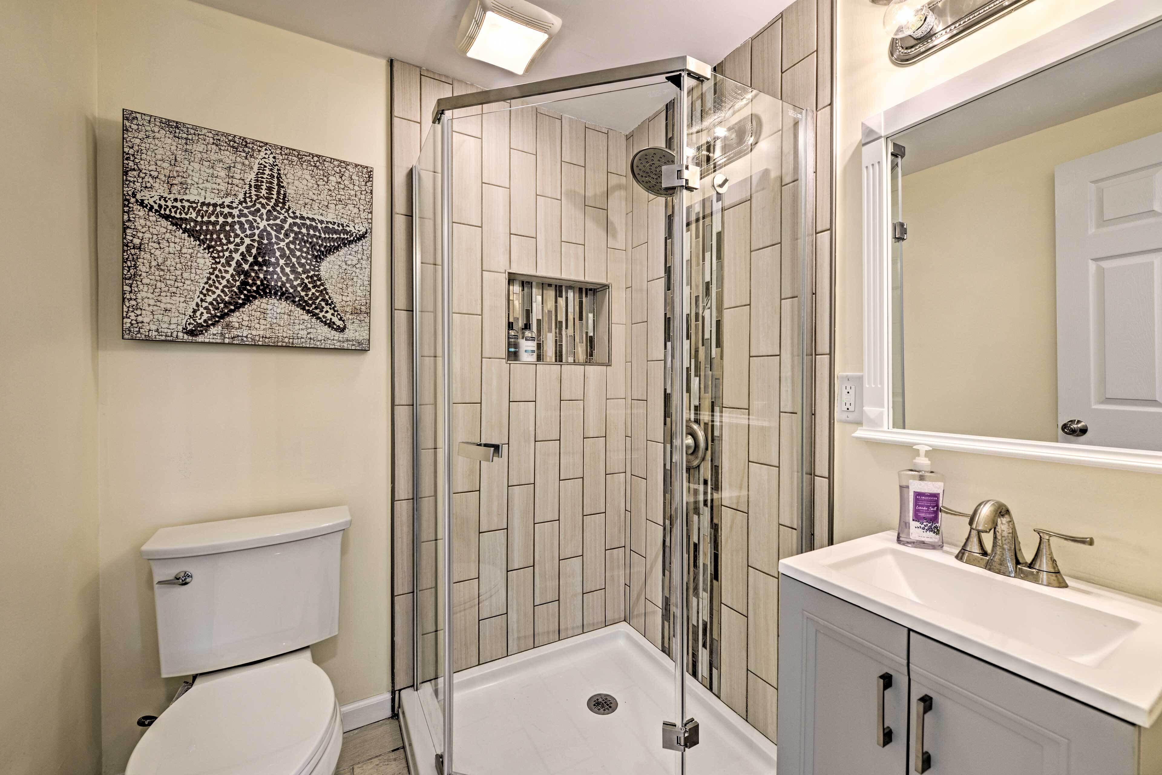 Une salle de bain moderne avec une douche à parois de verre, des toilettes et un lavabo surmonté d’un miroir.
