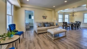 A spacious living room with a beige sofa, a blue armchair, and a dining area with a wooden table and chairs. - Seaside Wildwood Haven: Walk to Boardwalk/beach! (Wildwood Crest)