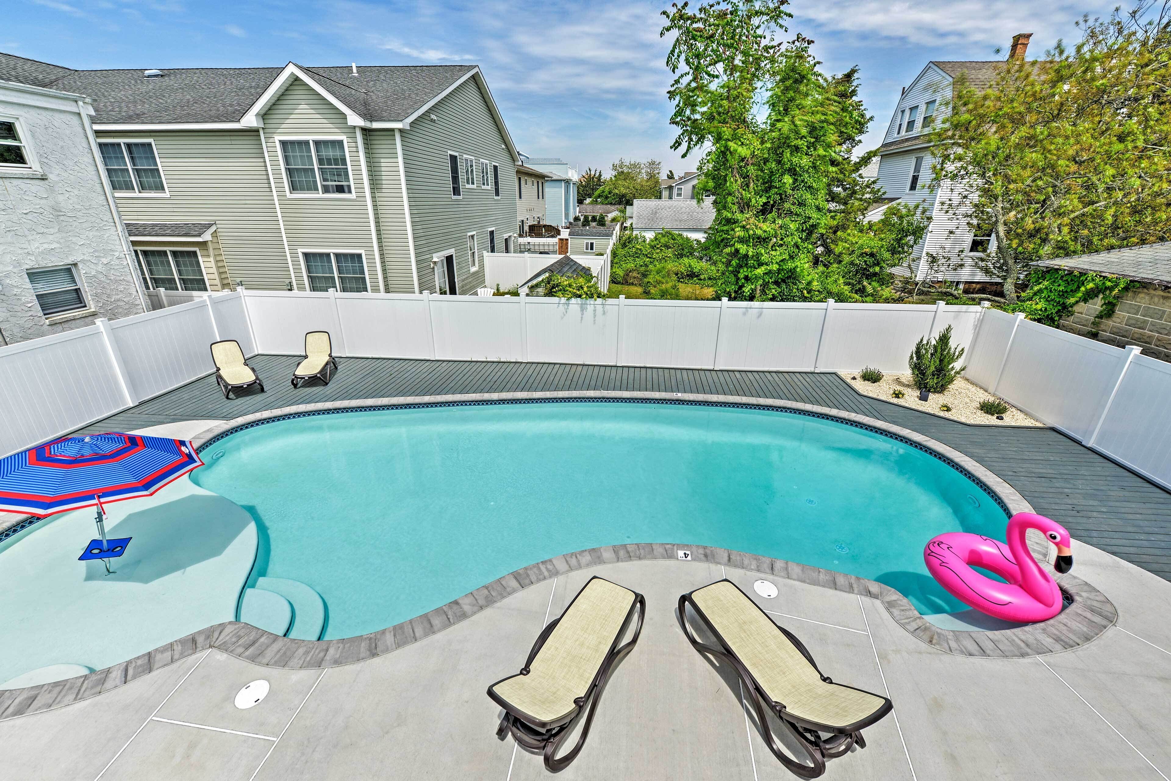 Un jardin avec une piscine, des chaises longues et un flotteur en forme de flamant rose.