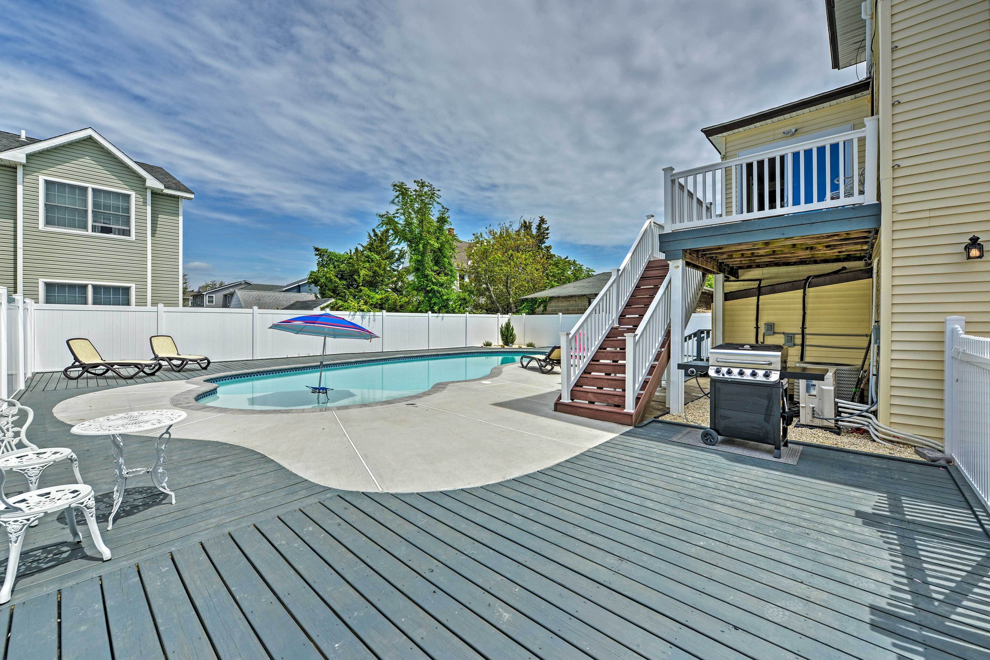 Un jardin avec une piscine, des chaises longues, un barbecue et un patio couvert.