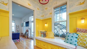 A bright yellow room with a large window, a built-in bench with cushions, and a view of the outdoors. - Carlton Landing Home w/ Poolside Lake View! (Eufaula)