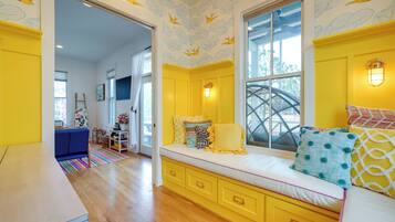 A bright yellow room with a large window, a built-in bench with cushions, and a view of the outdoors.