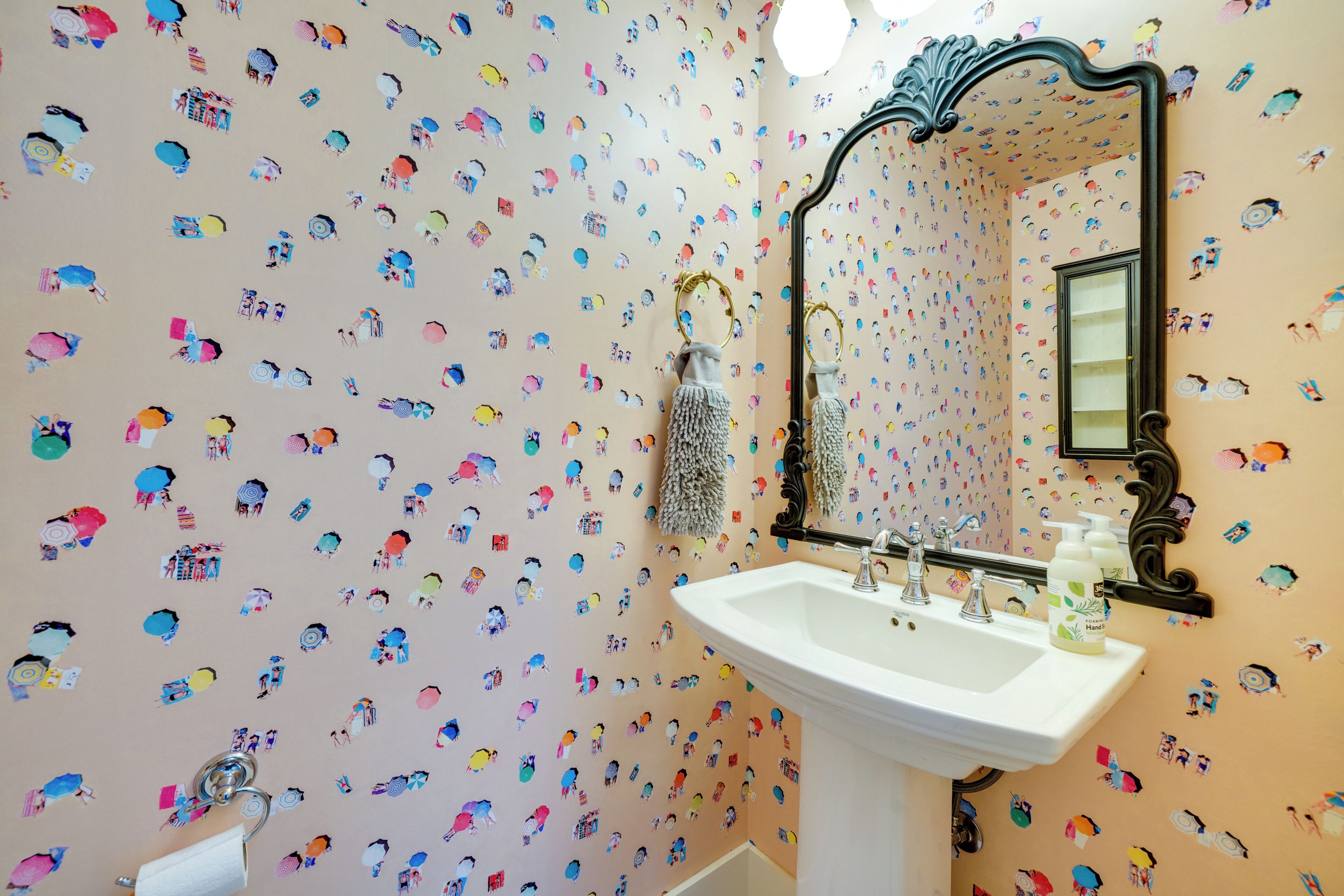 Une salle de bain équipée d’un lavabo, d’un miroir et d’autocollants décoratifs sur les murs.