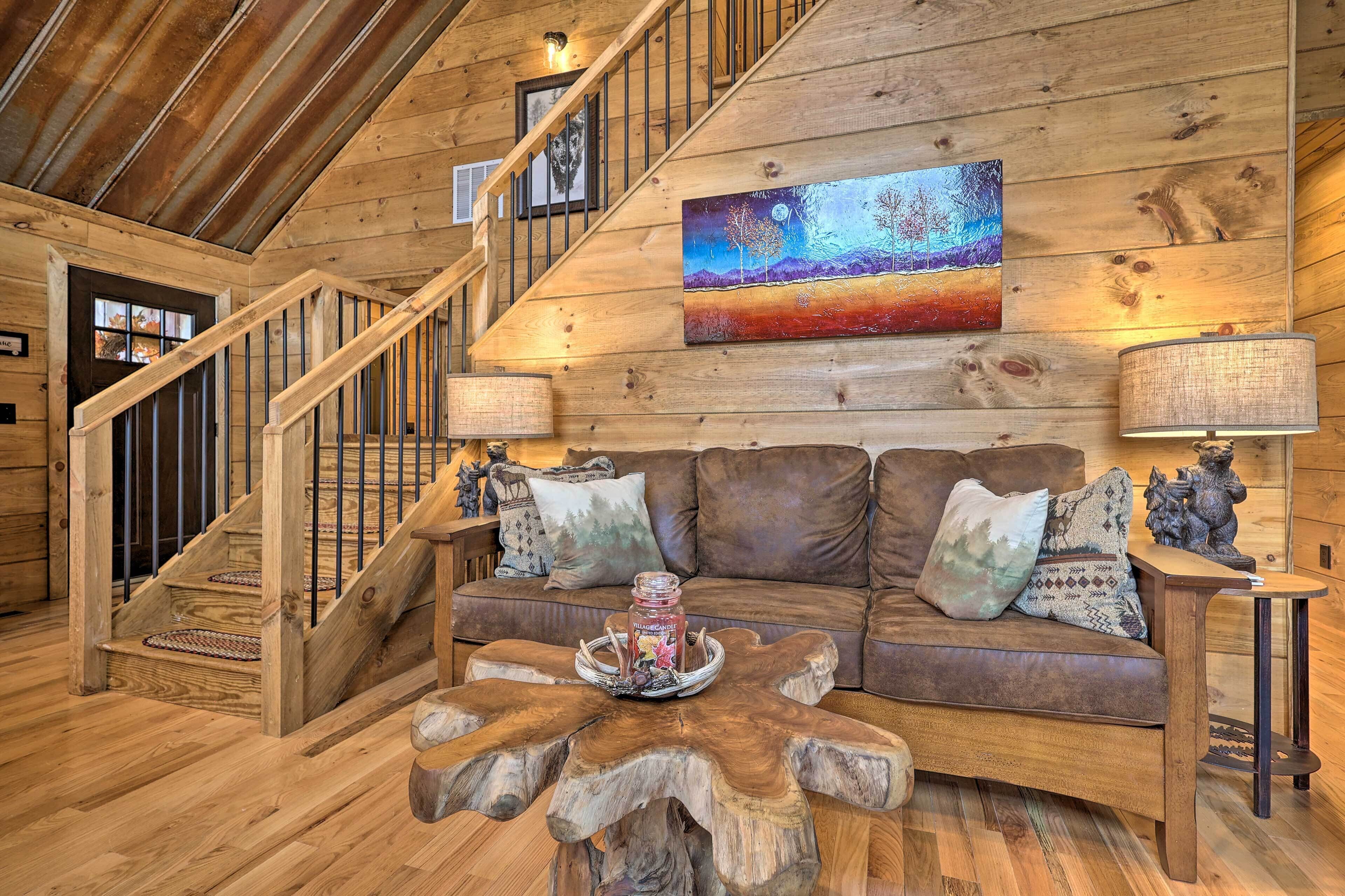 A wooden interior with a staircase, a couch, and a painting on the wall.