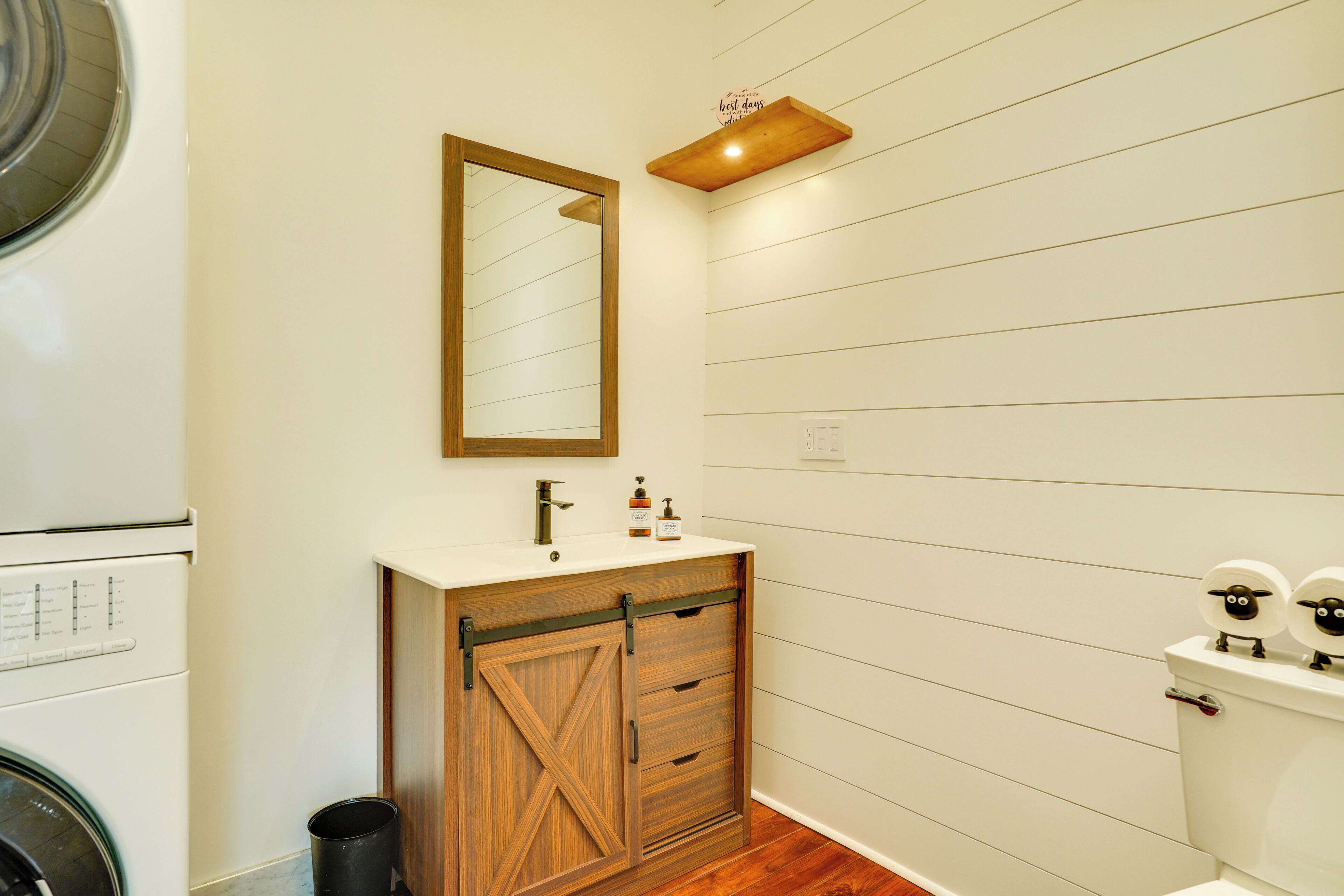 Une salle de bain avec un meuble-lavabo en bois, un miroir, un lavabo et des toilettes.