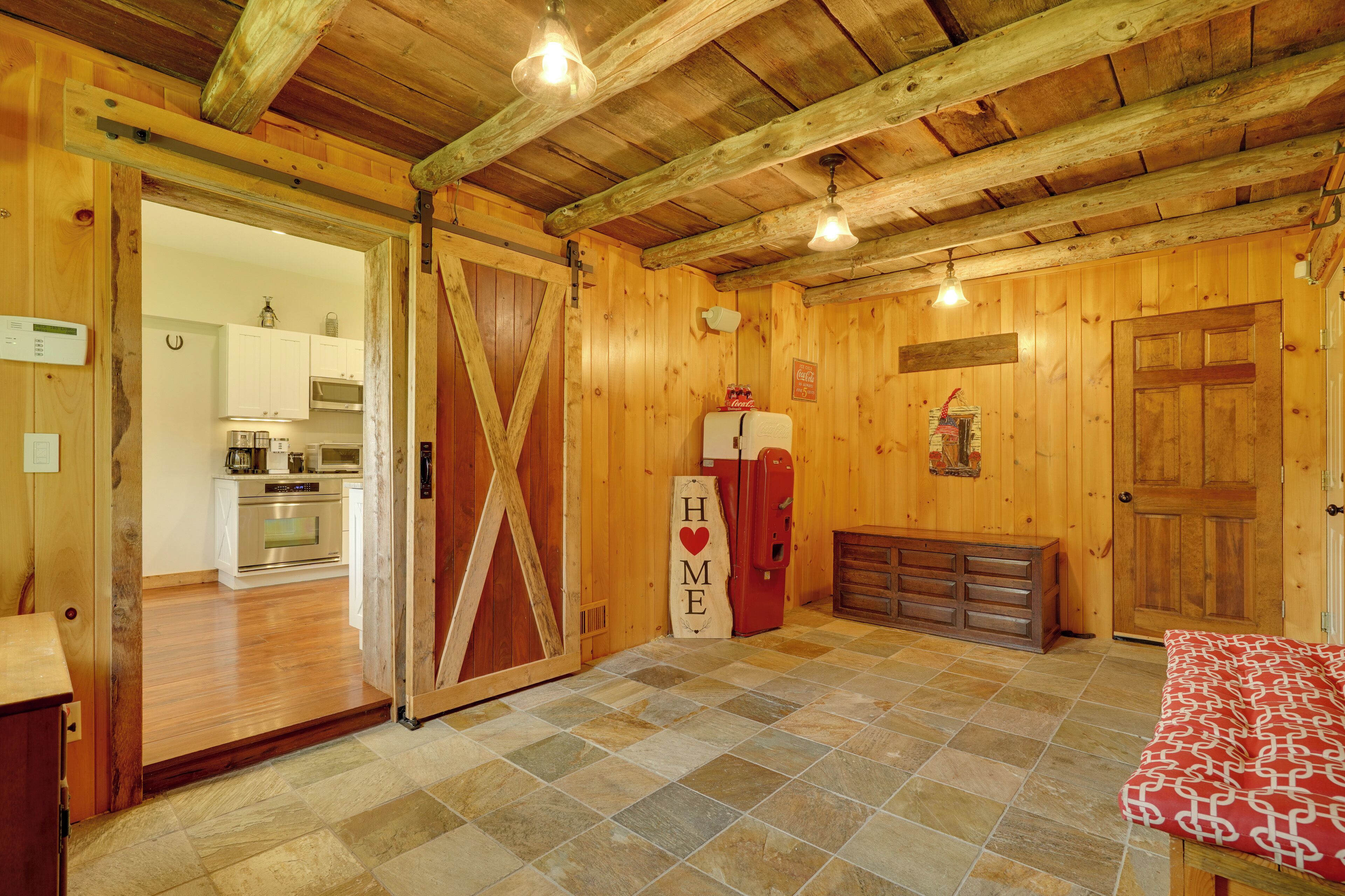 Un intérieur rustique avec des murs en bois, un sol à carreaux, un réfrigérateur et une porte sur laquelle est inscrit le mot « MAISON ».