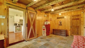 A rustic interior with wooden walls, a checkered floor, a refrigerator, and a door with a 'HOME' sign.
