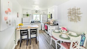 A modern kitchen with white cabinetry, a dining area with a round table, and a small island with a sink. - Cozy Monterey Apartment - Walk to Wharf & Dtwn! (Monterey)