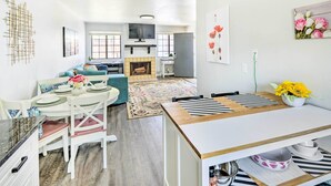 A modern living room with a dining area, kitchen, and fireplace. There are multiple seating options, including a sofa and chairs. - Cozy Monterey Apartment - Walk to Wharf & Dtwn! (Monterey)