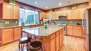 A modern kitchen with wooden cabinets, granite countertops, and stainless steel appliances. - Spacious Kent Home w/ Patio Near Seatac Airport (Kent)