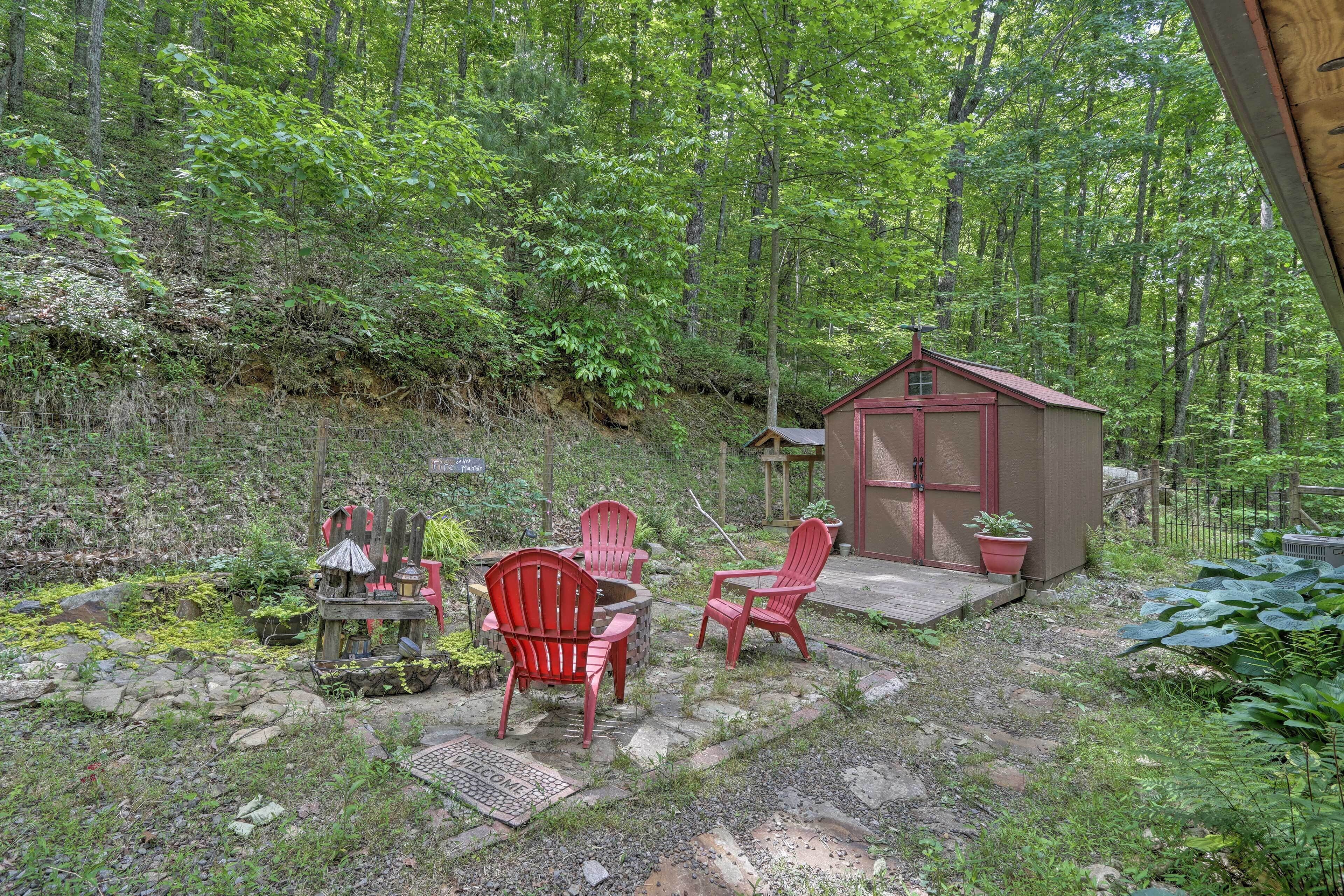 A rustic outdoor seating area with Adirondack chairs and a small wooden structure.