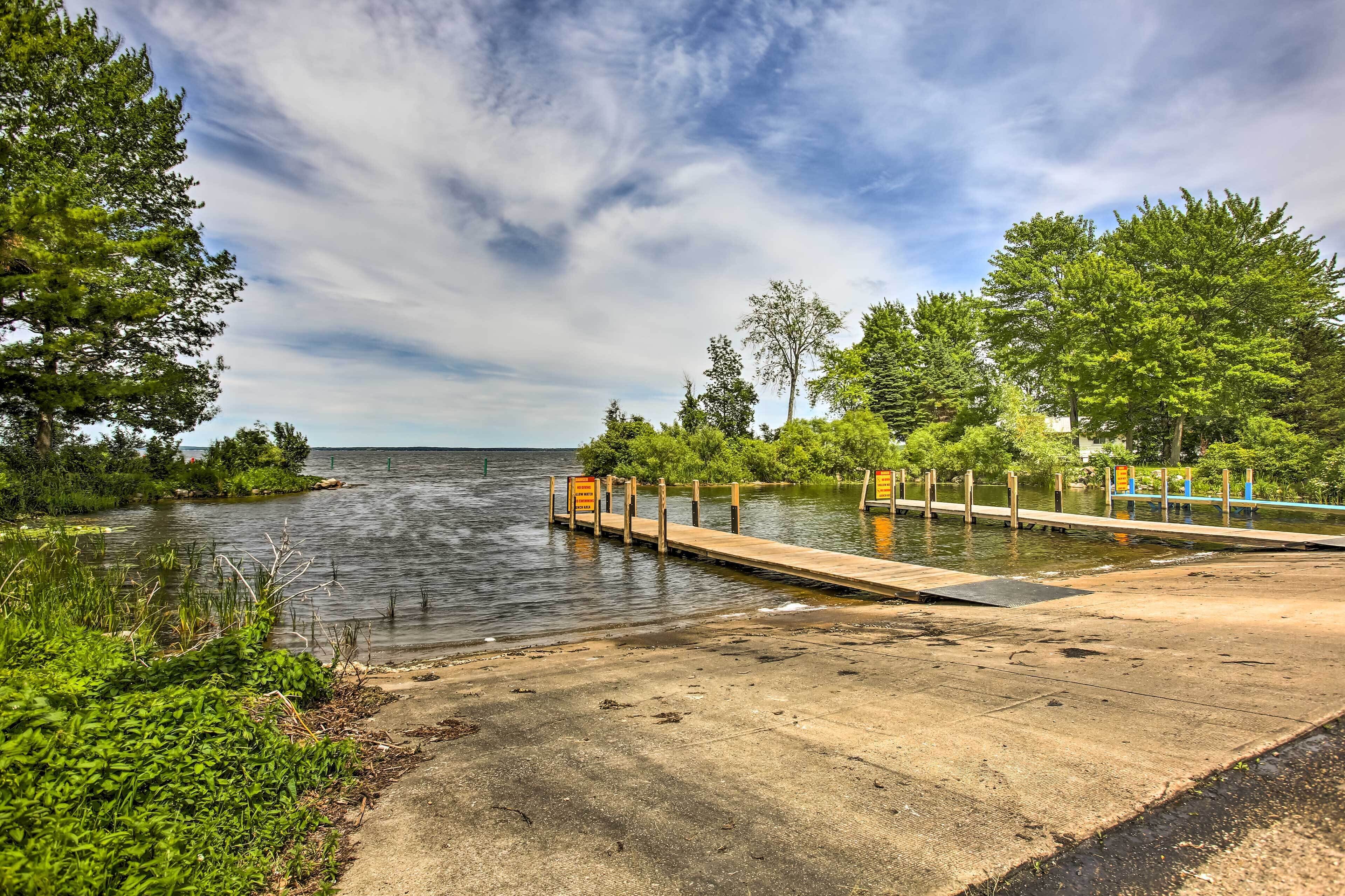 A concrete dock extending into a calm lake surrounded by lush greenery and trees.