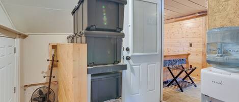 A room with a wooden door, a water dispenser, a fan, and a small table with a towel rack.