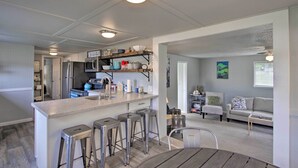 A modern kitchen with a bar area, a dining table, and a living area with a sofa and armchair. - Waterfront Anderson Island Home w/ Kayaks (Anderson Island)