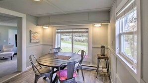 A dining area with a round table and chairs, a sign indicating the location, and a view of the outdoors through a large window. - Waterfront Anderson Island Home w/ Kayaks (Anderson Island)