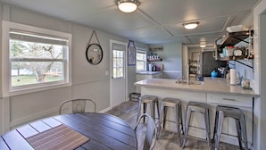 A modern kitchen with a central island, bar stools, and a dining table. - Waterfront Anderson Island Home w/ Kayaks (Anderson Island)
