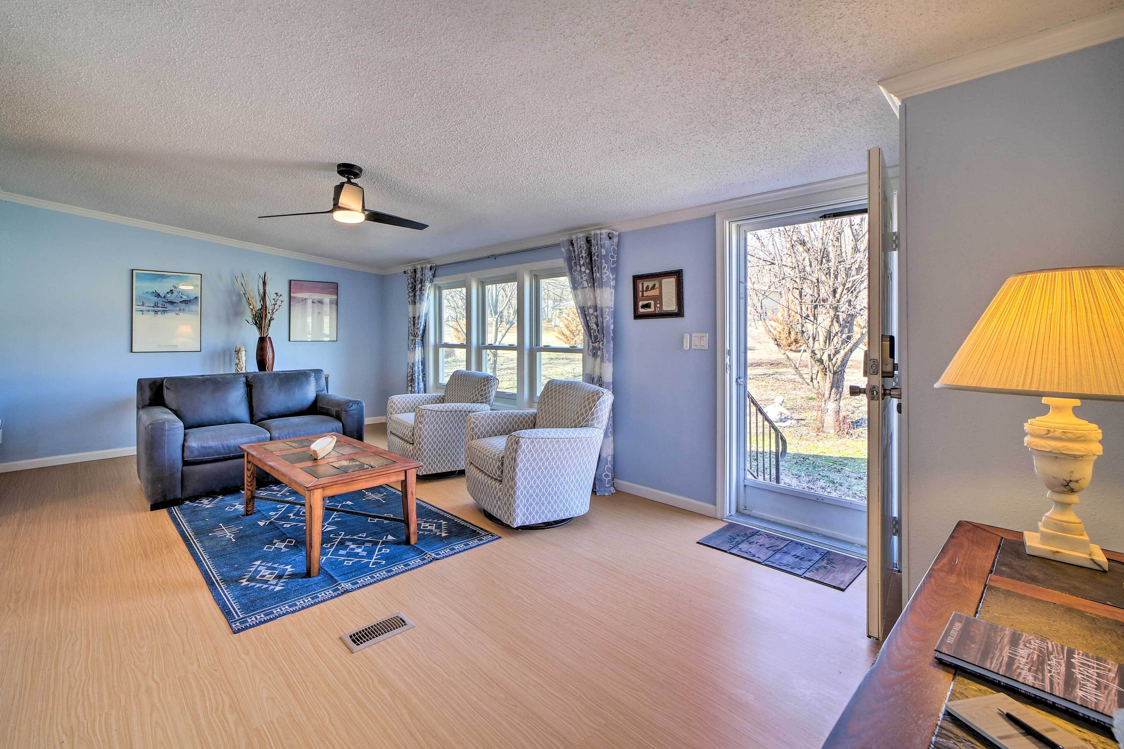 A living room with a sofa, armchairs, a coffee table, and a lamp.
