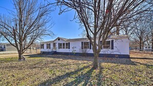 A single-story mobile home with a gabled roof, a front porch, and a small attached garage. - Family-friendly Bernice Home: 2 Mi to Lake & Park! (Afton)