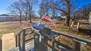 A barbecue grill with an American flag, a wooden deck, and a fenced yard with leaf-covered ground. - Family-friendly Bernice Home: 2 Mi to Lake & Park! (Afton)