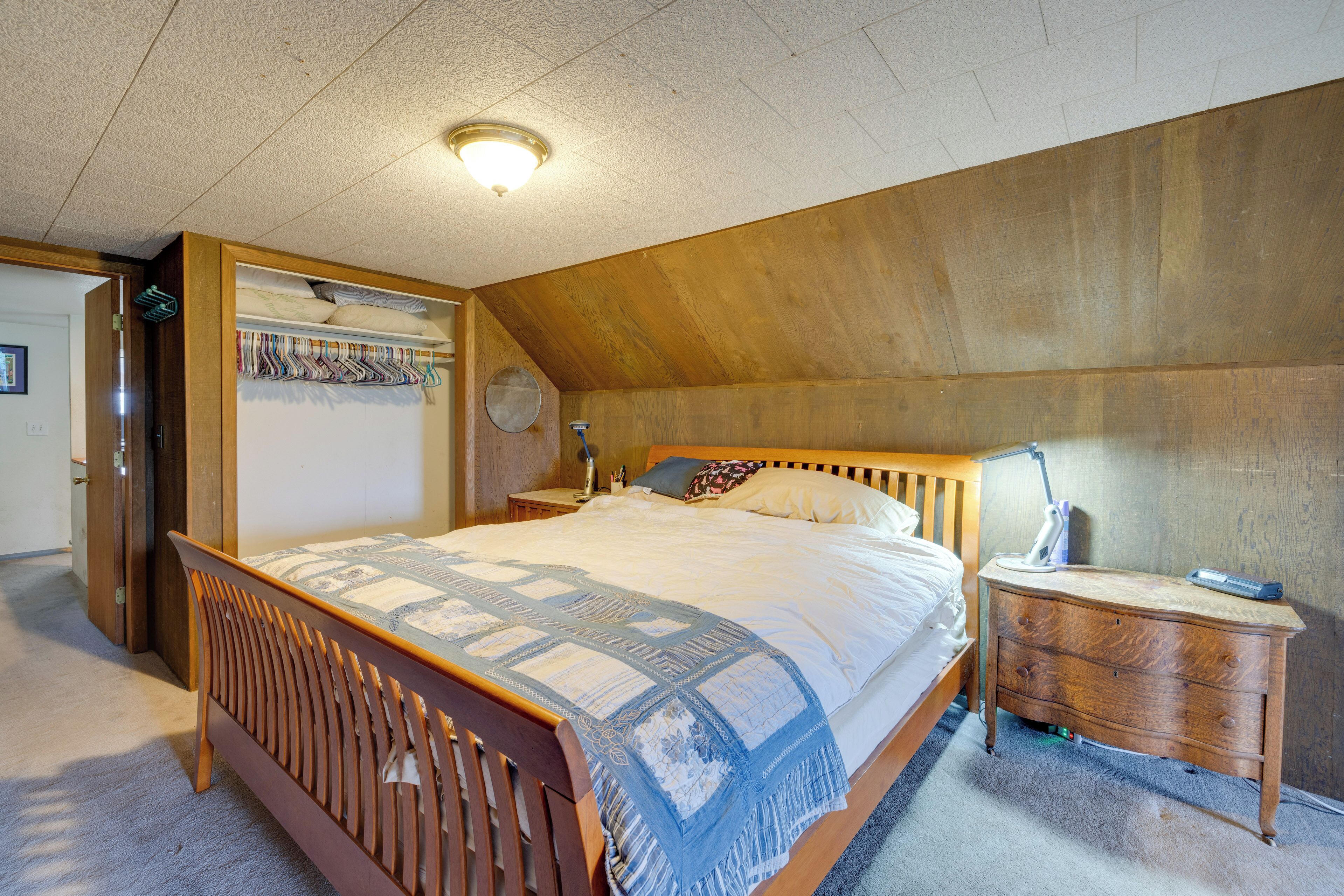 A bedroom with a wooden bed, a nightstand, and a dresser.