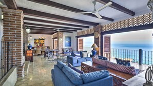 A spacious living area with blue sofas, a wooden coffee table, and a view of the ocean. - Mid-century Modern Condo w/ Patio & Ocean Views! (Puerto Vallarta)