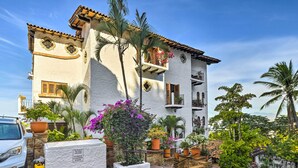 A white building with a tiled roof, balconies, and potted plants. - Mid-century Modern Condo w/ Patio & Ocean Views! (Puerto Vallarta)