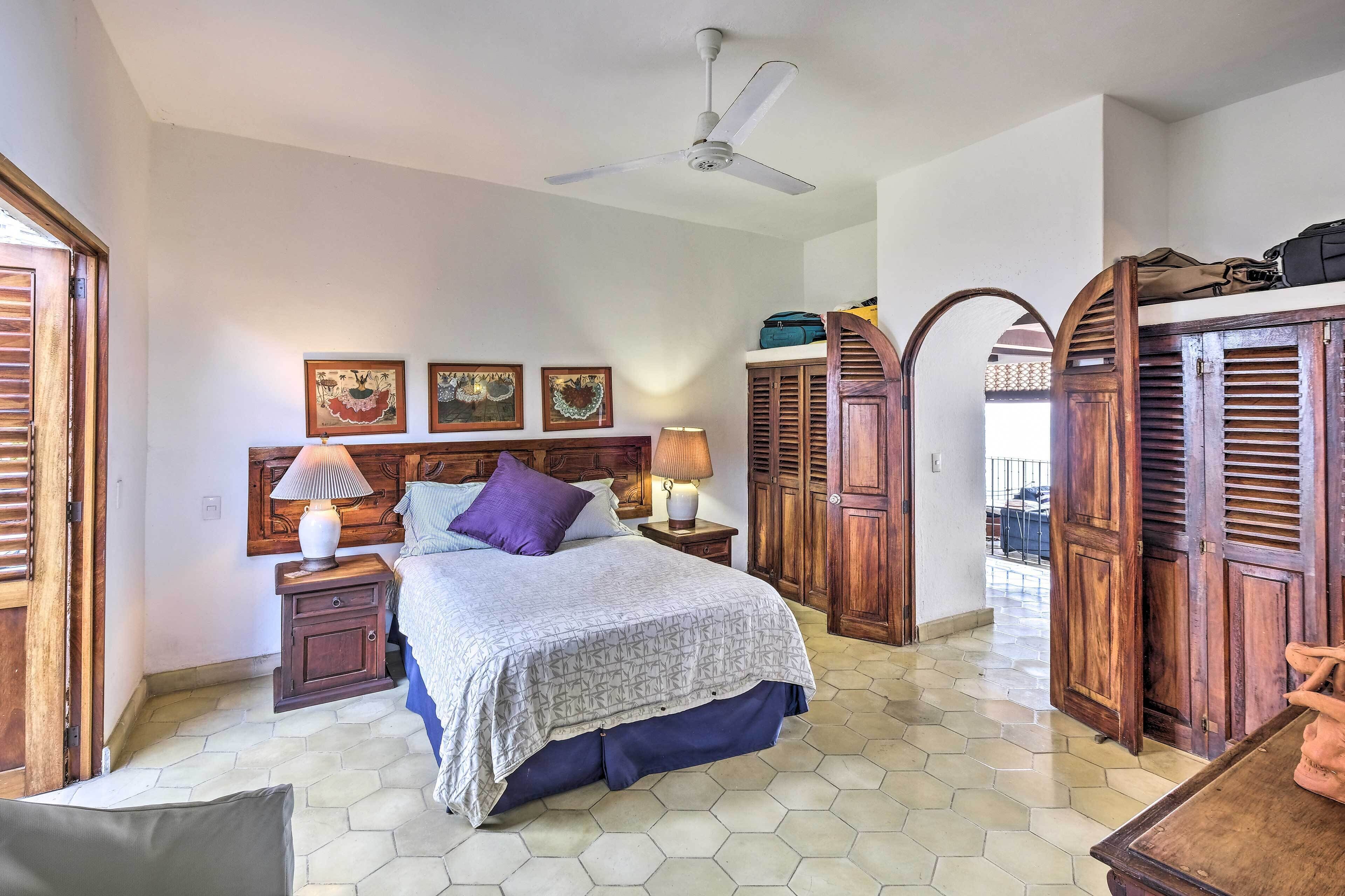 A bedroom with a bed, wooden wardrobe, and a ceiling fan.