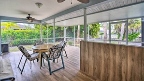 A spacious patio with a wooden table and chairs, large windows, and ceiling fans. - Pool Access & Beach Gear! Canalfront Naples Home (Naples)