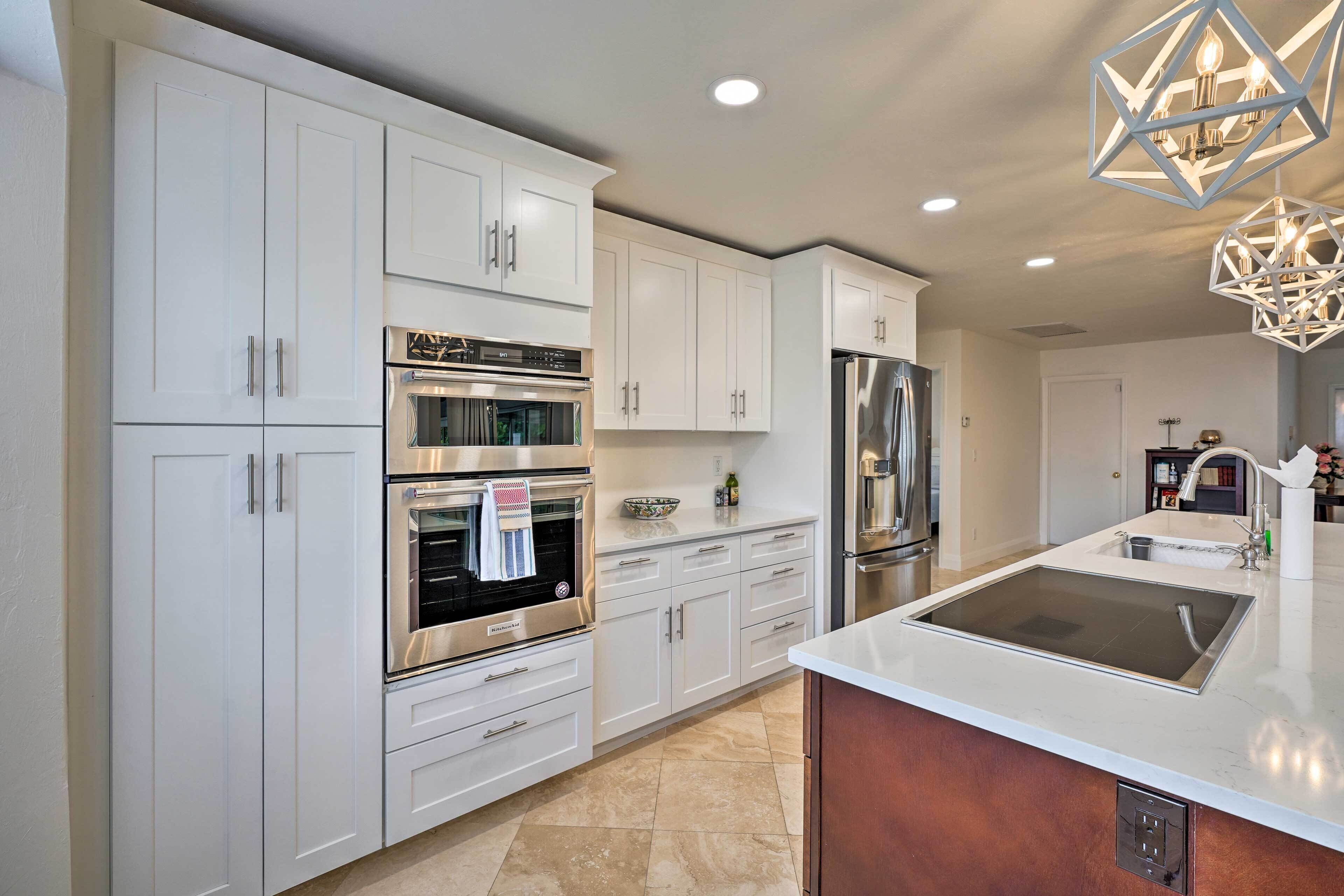 A modern kitchen with white cabinetry, stainless steel appliances, and a central island.