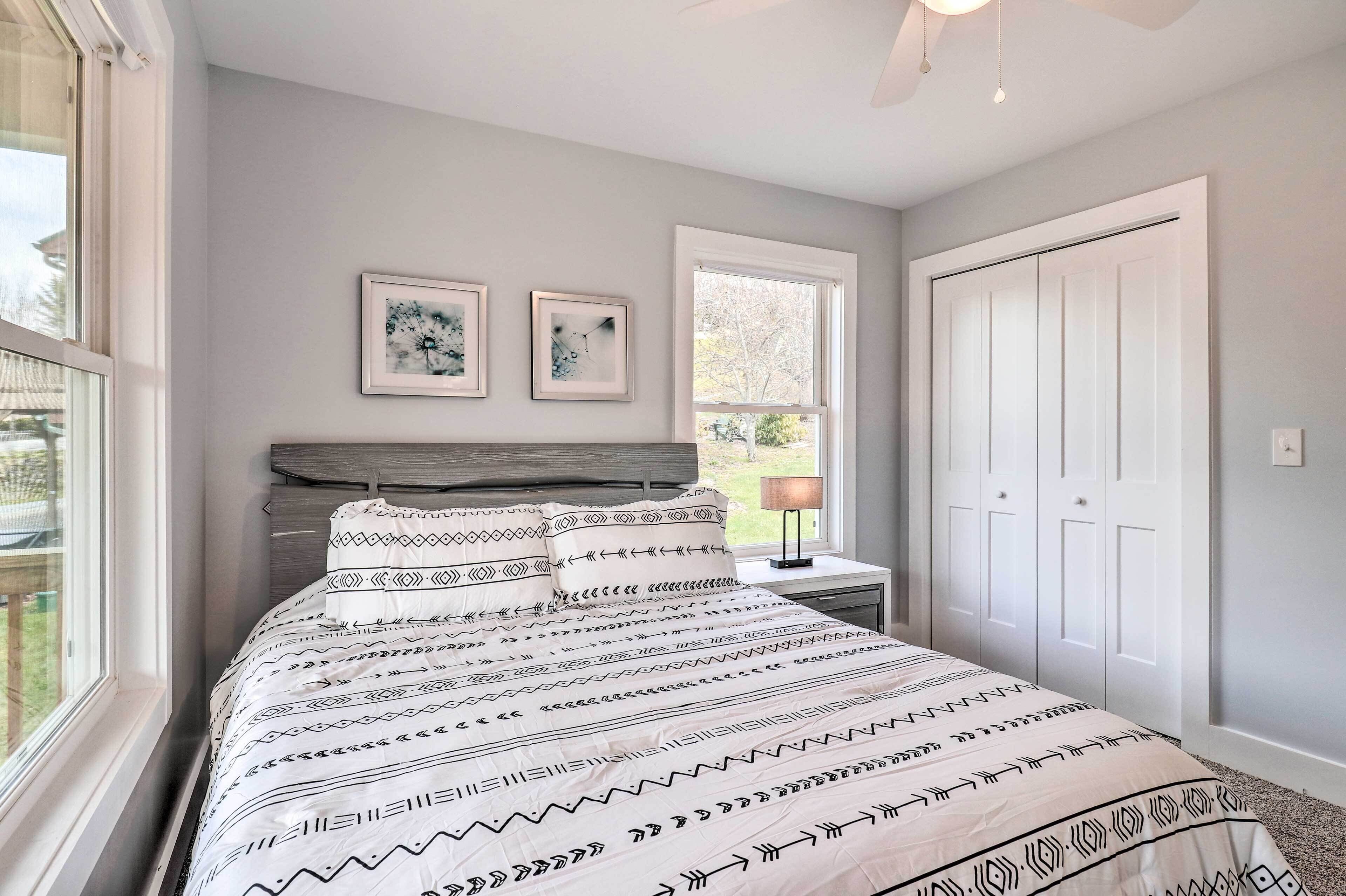 Une chambre à coucher avec un lit, deux tableaux encadrés, une table de chevet et une fenêtre.