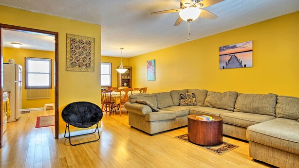 A living room with a sectional sofa, a black chair, a wooden coffee table, and a ceiling fan.