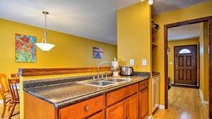A kitchen with wooden cabinets, granite countertops, a built-in sink, and a hanging light fixture.