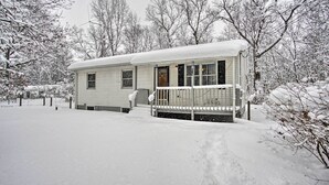 A single-story house with a covered porch and a small front yard, surrounded by snow-covered trees.