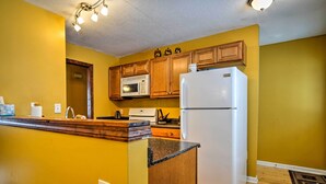 A kitchen with wooden cabinets, a white refrigerator, a microwave, and a granite countertop.