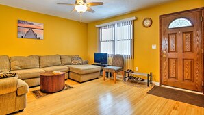 A living room with a sofa, a coffee table, a television, and a door.