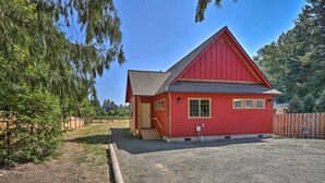 En rød bygning med skråt tag, en lille veranda og en grusbelagt indkørsel.