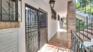 A corridor with white walls, a brick column, and a staircase with metal railings.