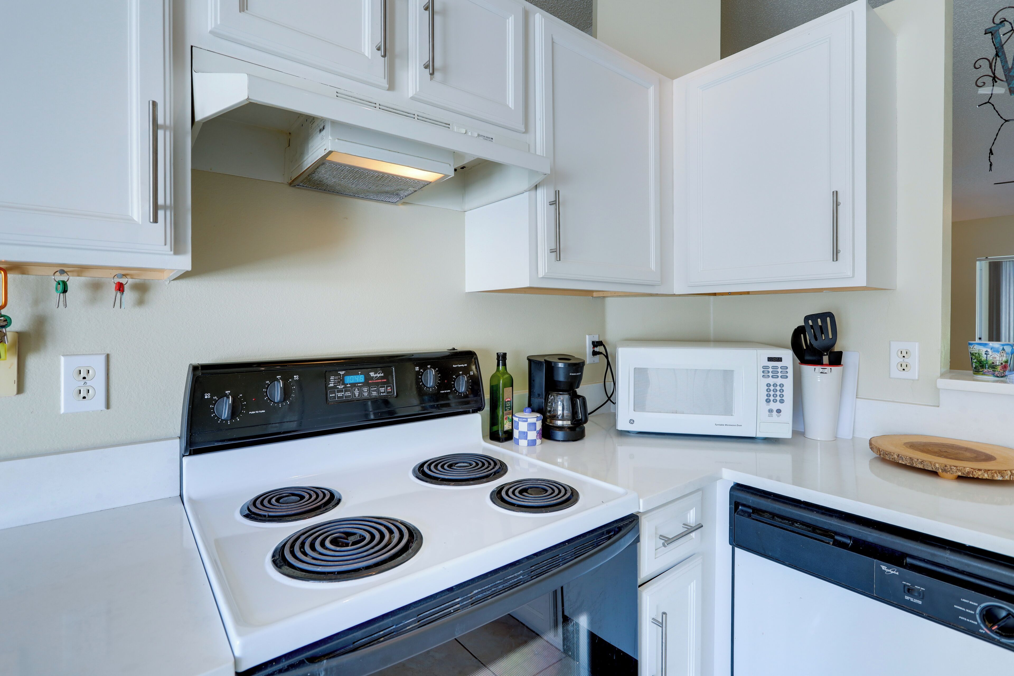 A kitchen with white cabinets, a stove, a microwave, and a dishwasher.