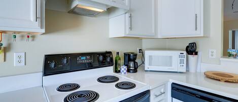 A kitchen with white cabinets, a stove, a microwave, and a dishwasher.