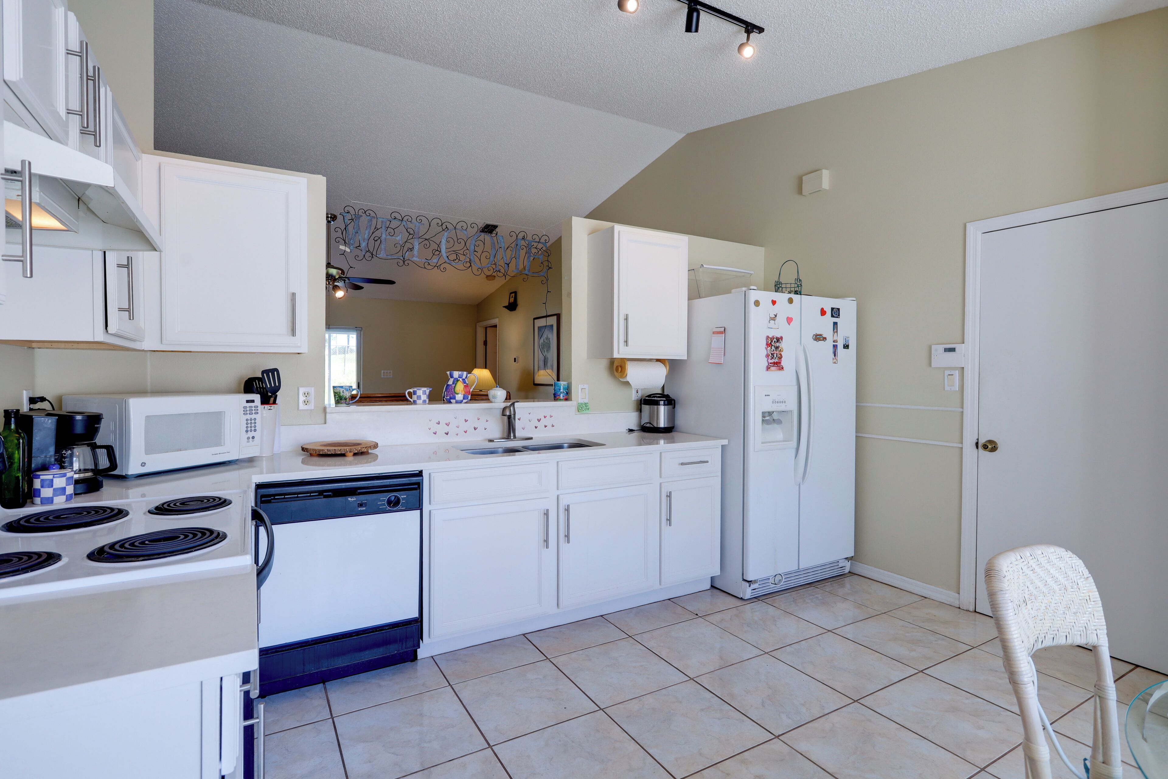 A modern kitchen with white cabinetry, a stove, microwave, and refrigerator.