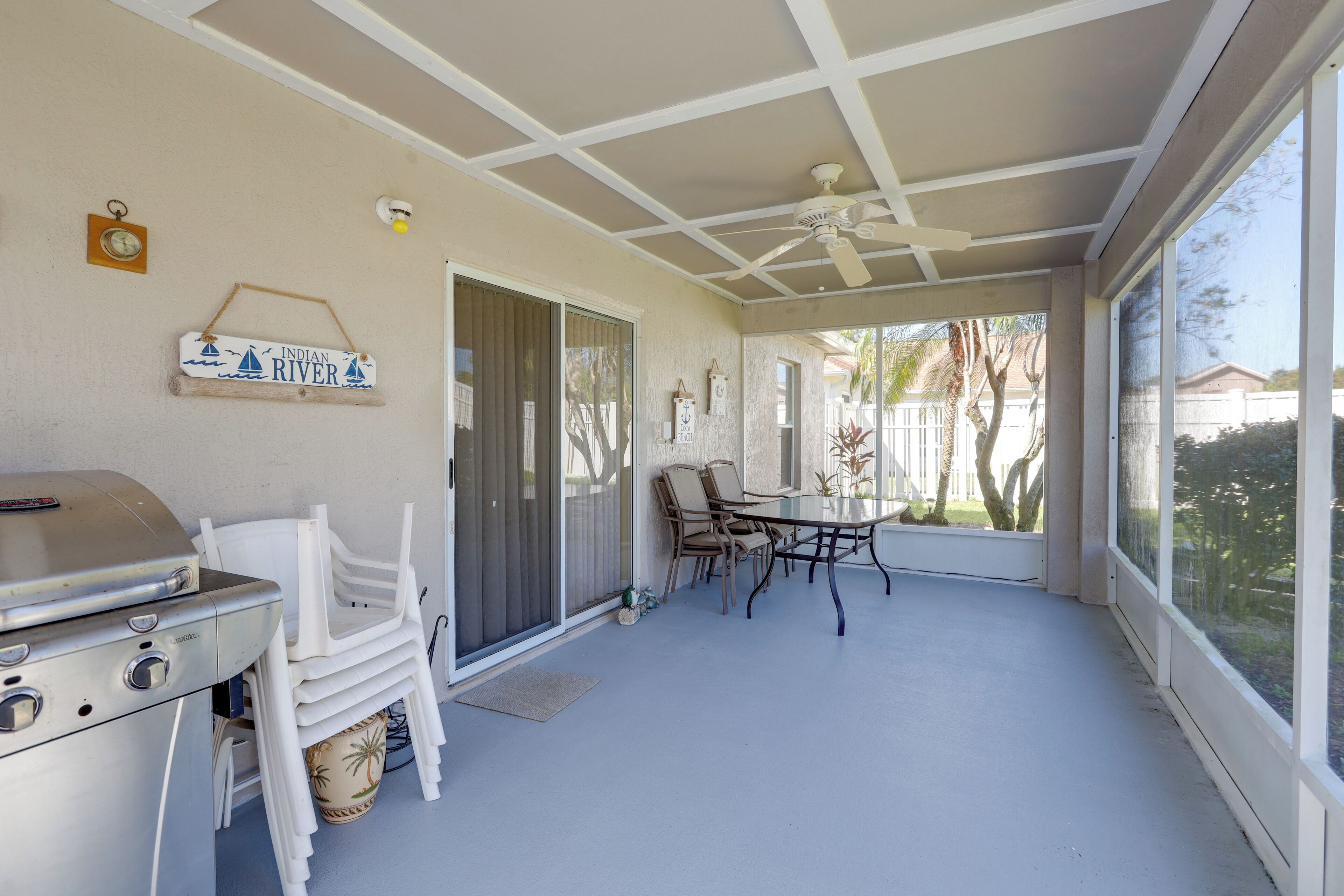 A covered patio with a grill, chairs, and a table.