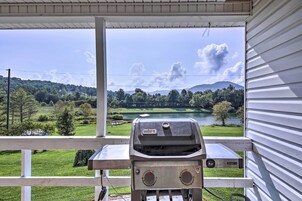 Una parrilla en un porche con vistas a un lago y colinas.