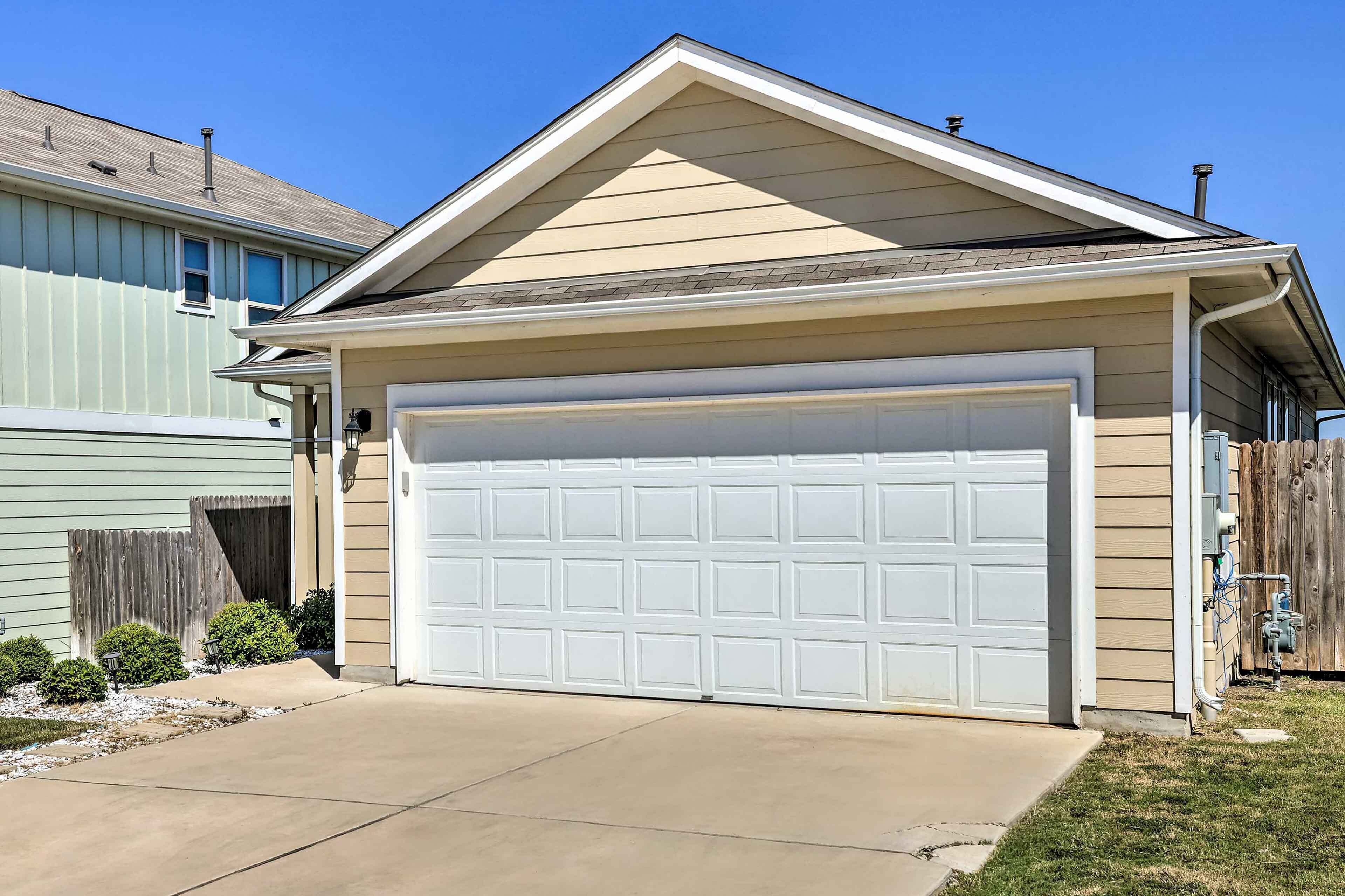 A single-story house with a beige exterior, a white garage door, and a sloped roof.
