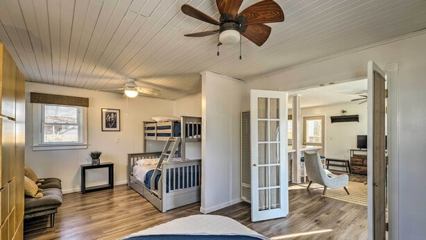 A bedroom with a bunk bed, a ceiling fan, a window with blinds, and a door leading to another room. - Fire Pit & Grill: Lakeview Mecosta Cottage! (Mecosta)