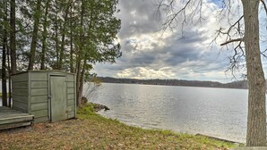 A lakeside cabin with a dock, surrounded by trees and a clear view of the lake. - Fire Pit & Grill: Lakeview Mecosta Cottage! (Mecosta)