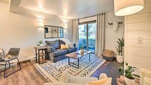 Ein modernes Wohnzimmer mit einer Couch, einem Couchtisch und Sesseln, ein Essbereich mit Tisch und Stühlen sowie ein Balkon mit Blick.