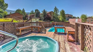 Eine Holzterrasse mit Whirlpool, Pool und Gartenmöbeln.