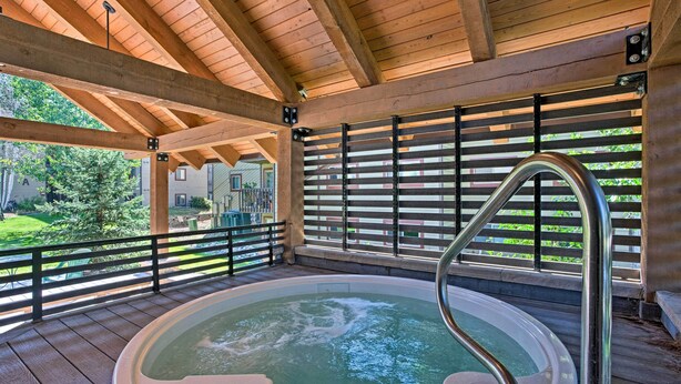 Eine Holzterrasse mit Whirlpool, Metallgeländern und Blick auf ein Wohngebiet.