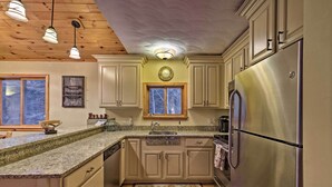 Eine Küche mit Holzausstattung, einem Edelstahlkühlschrank, Granit Arbeitsplatten und einer Holzbalkendecke.