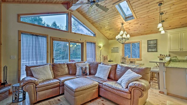Ein geräumiges Wohnzimmer mit einer großzügigen, ledernen L-Form-Couch, Holzböden und einem Deckenventilator.